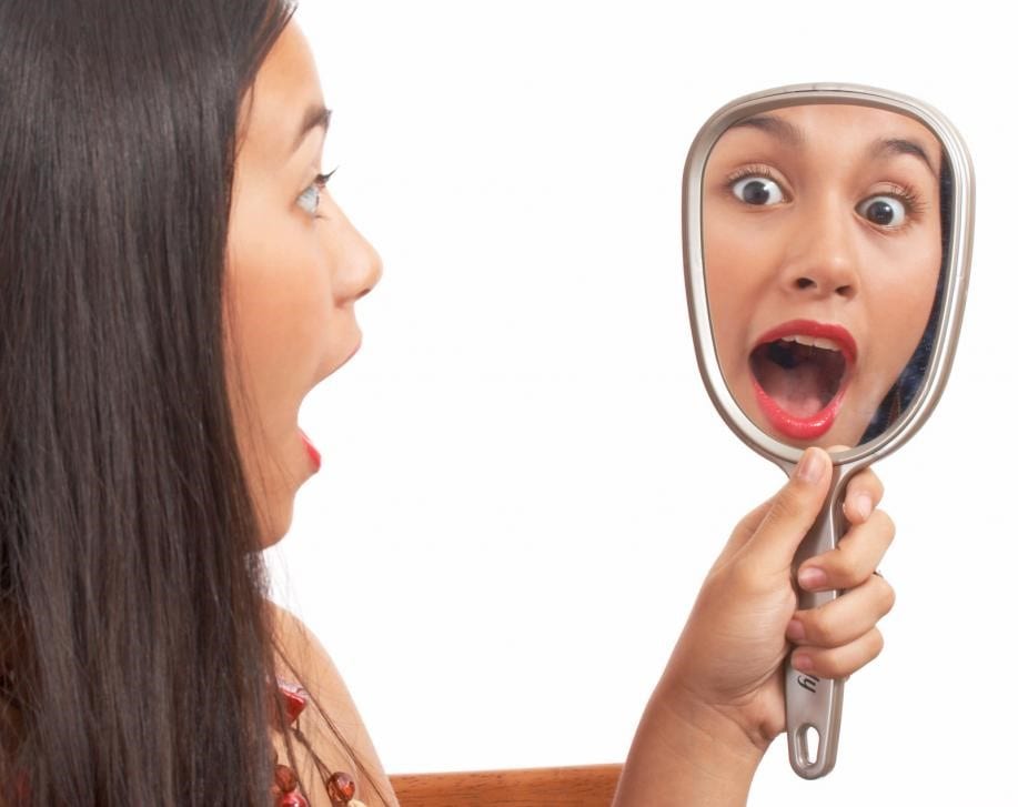 Girl looking into a mirror and getting shocked